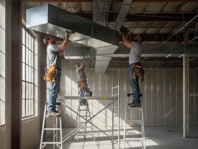 Technician installing new ductwork for a home heating and cooling system