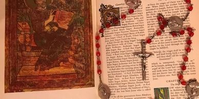 An open book with a rosary draped across its pages.