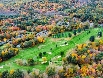 A vibrant autumn golf course surrounded by colorful fall trees.