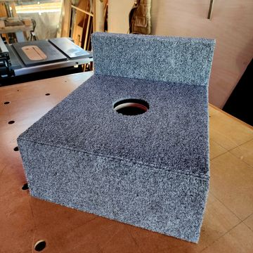 A carpeted wooden box with a circular hole in the center.