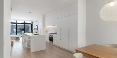 Modern white kitchen with island and wooden dining table.