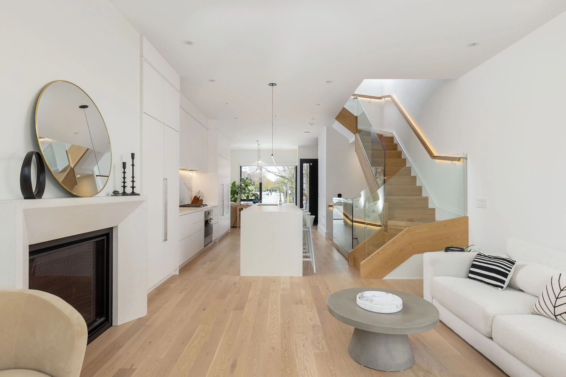 Modern white kitchen with wooden stairs and minimalist decor.