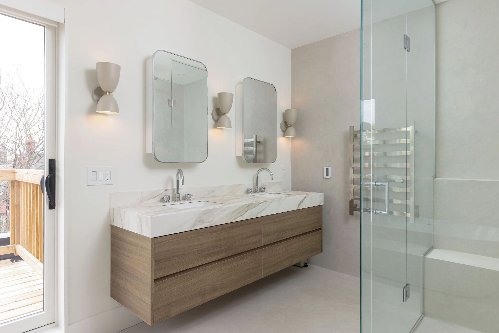 Modern bathroom with double sinks and glass shower.