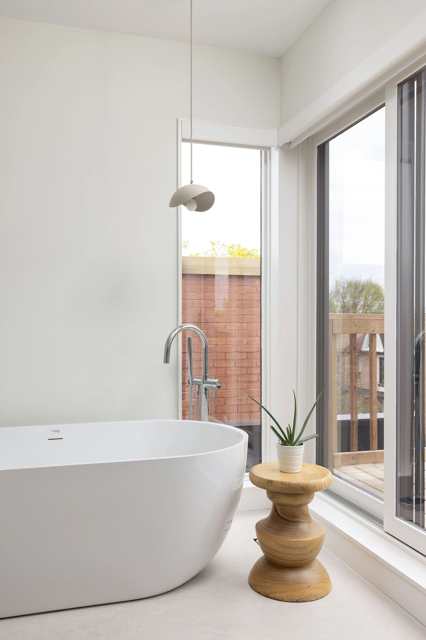 Modern white bathtub next to a large window.