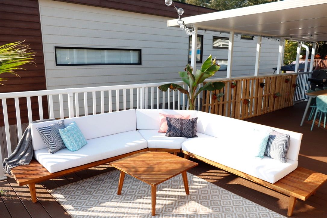 Modern outdoor patio seating with cushions and wooden table.