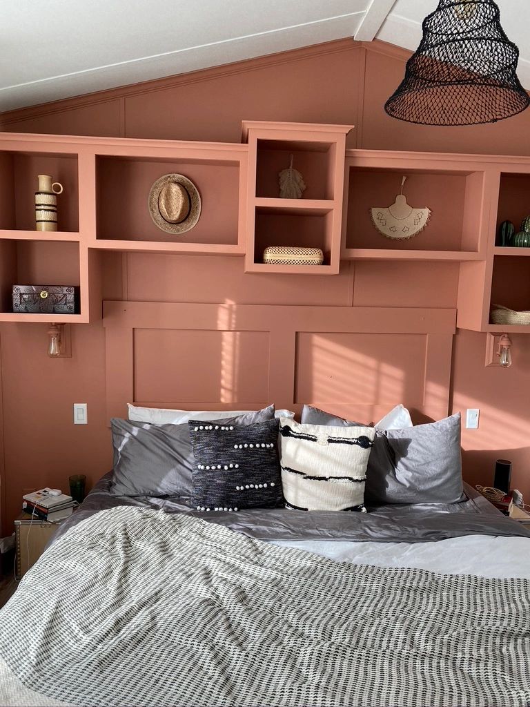 Cozy bedroom with coral walls and decorative shelves.