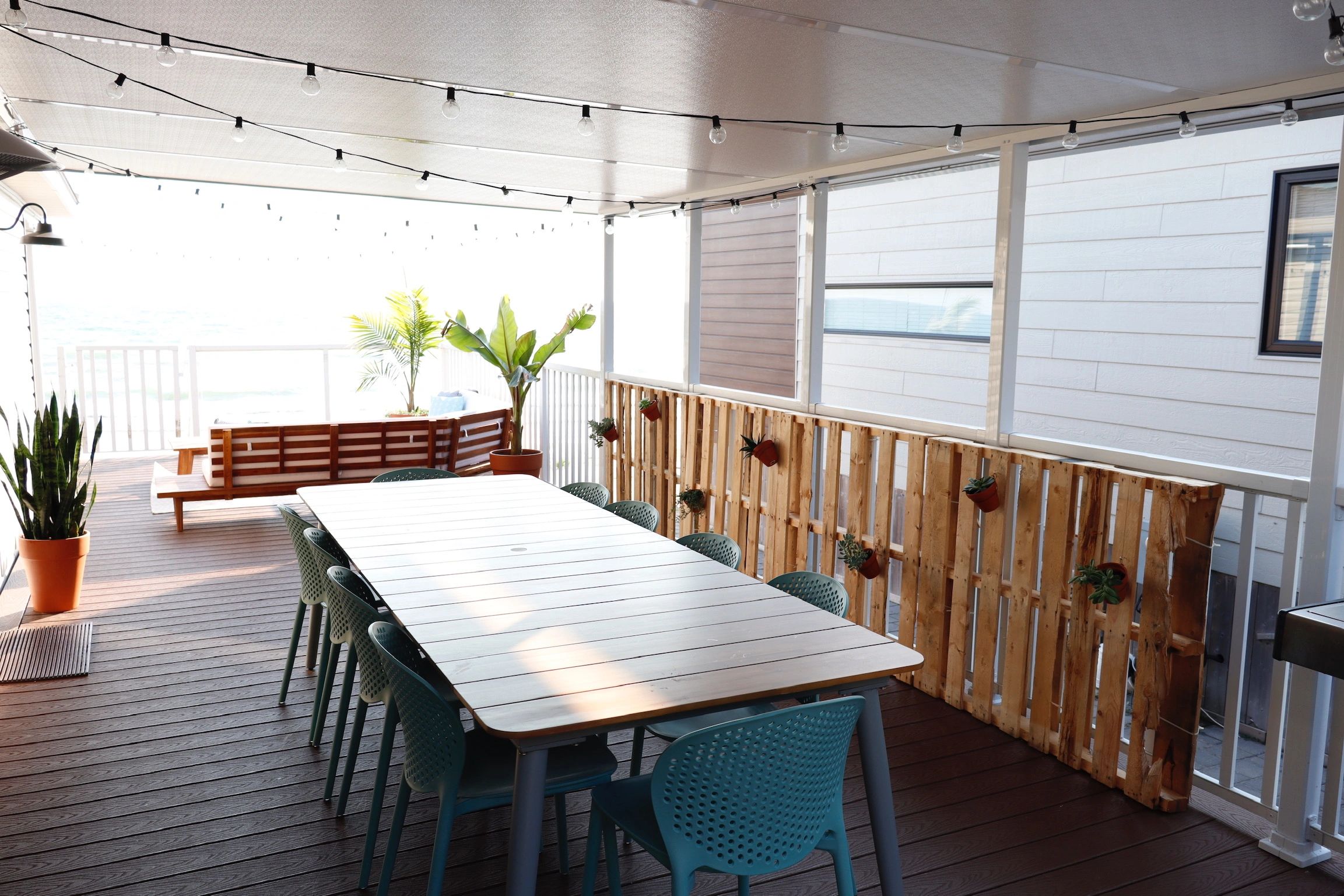 Modern outdoor dining space with plants and string lights.