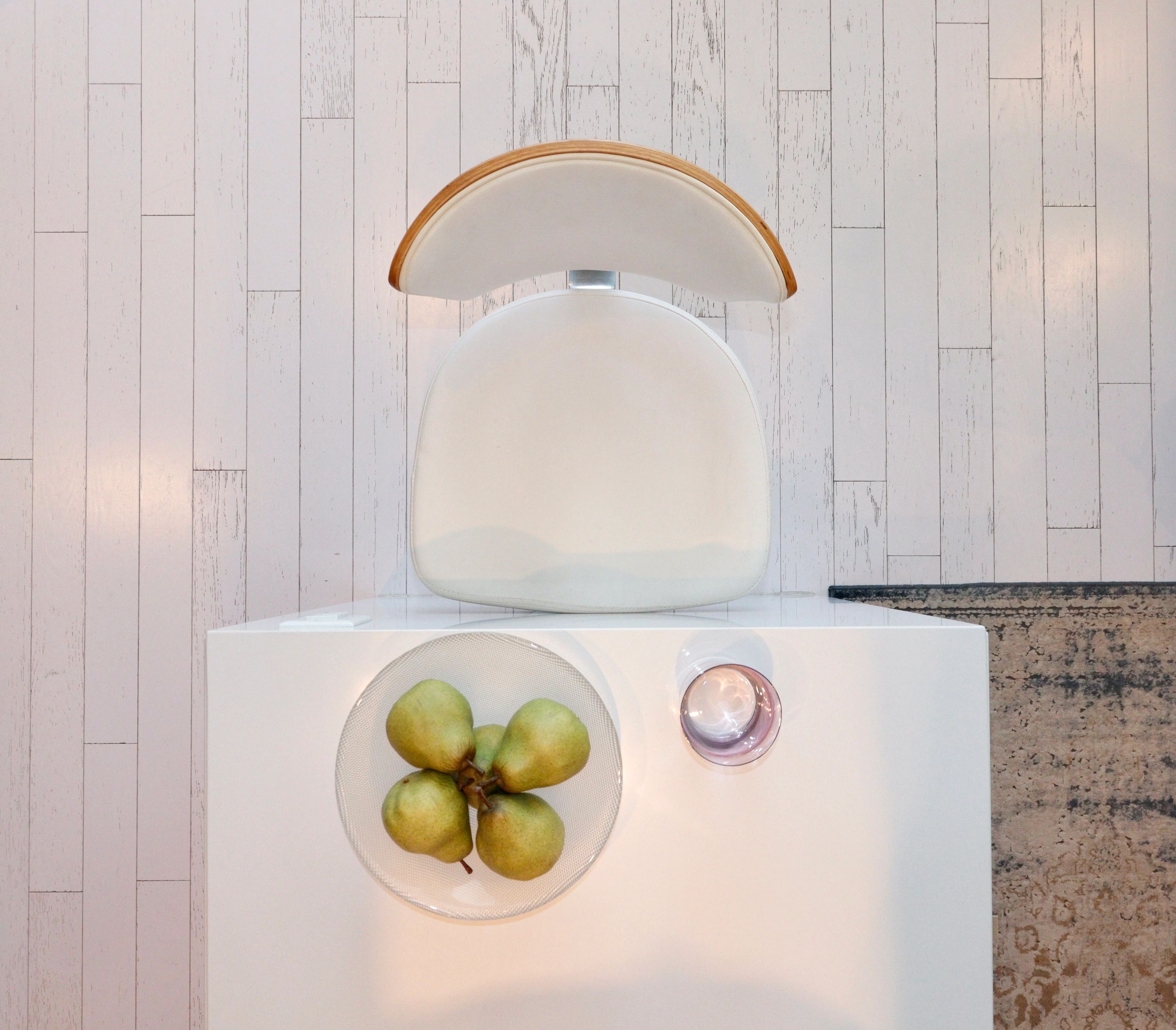 White chair and table with pears and glass on white wooden floor.