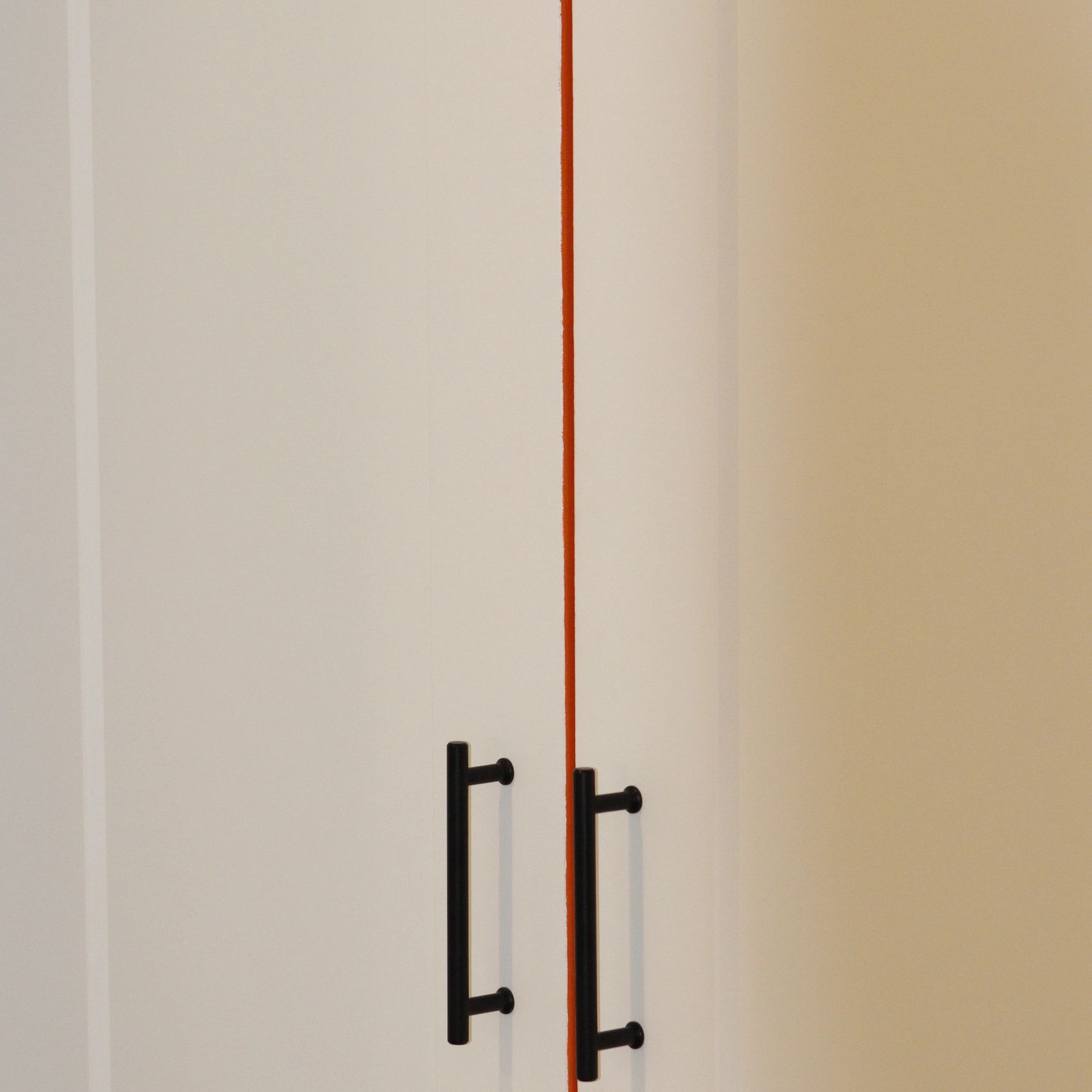 Black door handles on white doors with a red line in between.