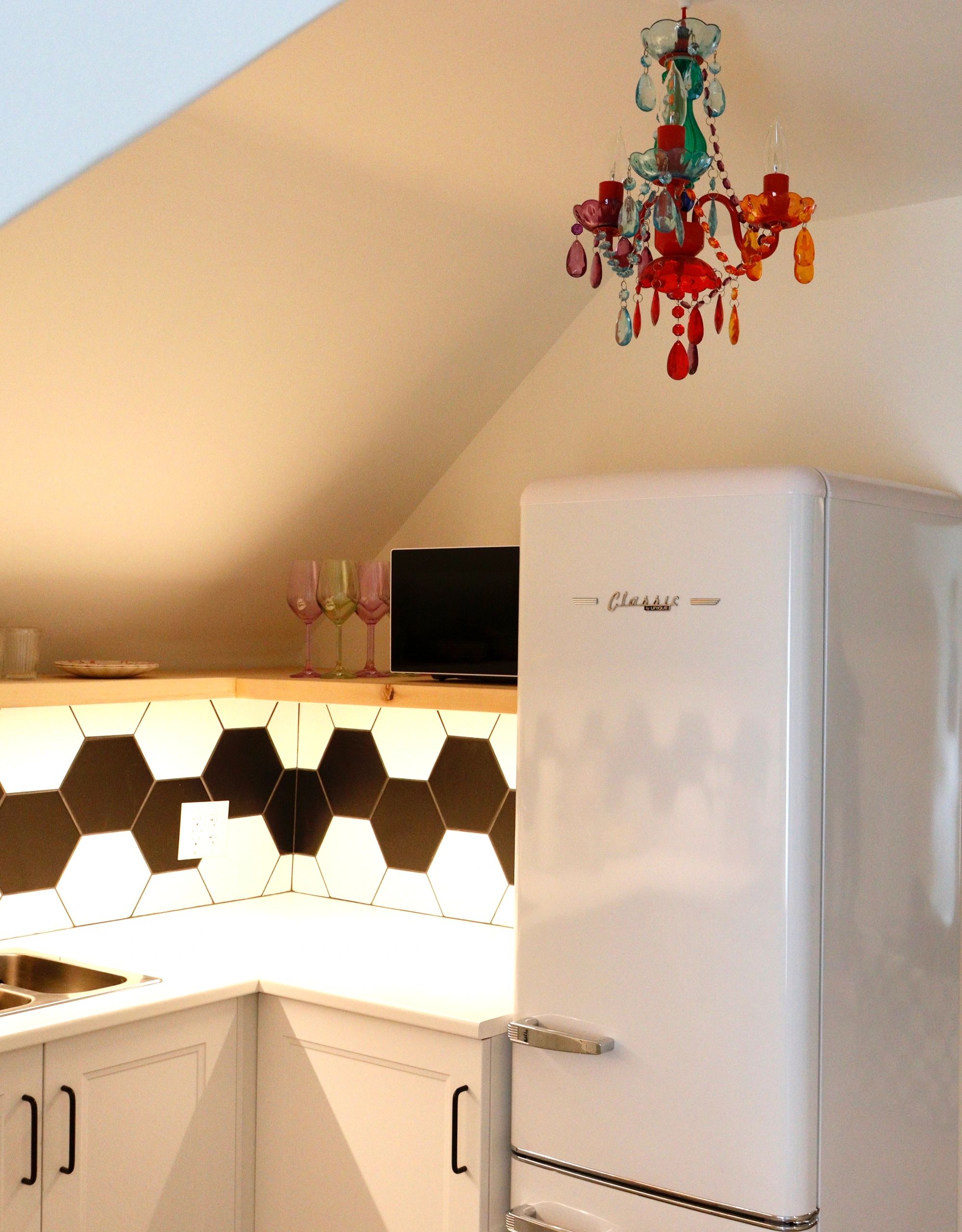 Bright kitchen with retro fridge and colorful chandelier.