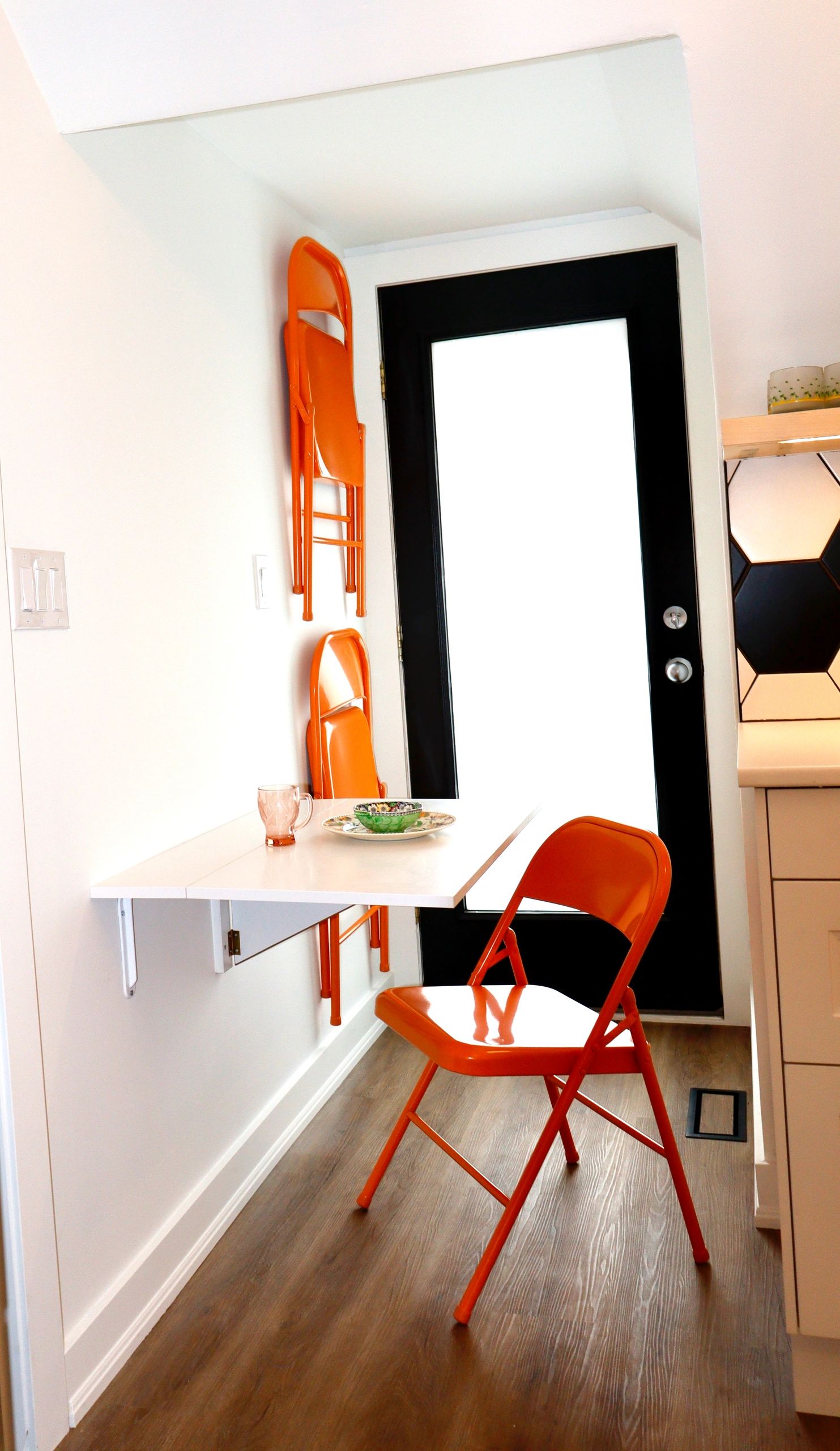 Compact kitchen nook with orange chairs and a foldable table.