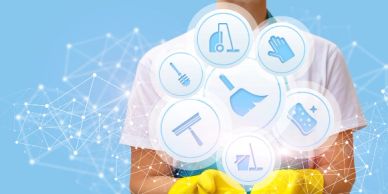 Person in yellow gloves holding cleaning icons.