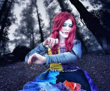 woman in Sally costume from Nightmare before Christmas sewing her arm together in a dark forest