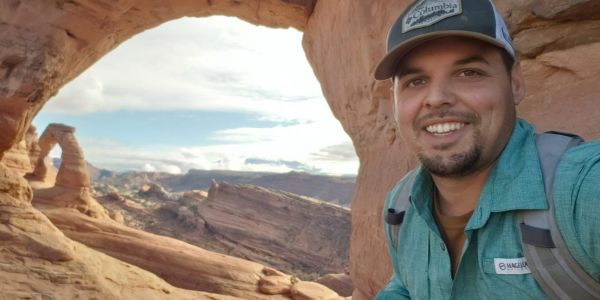 Smiling man taking selfie at a rock formation.