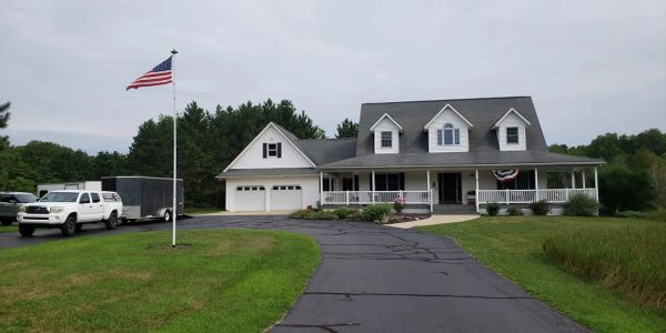 American house with a wrap-around porch and flag.