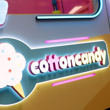 Bright neon sign displaying 'cottoncandy' with an ice cream cone graphic.