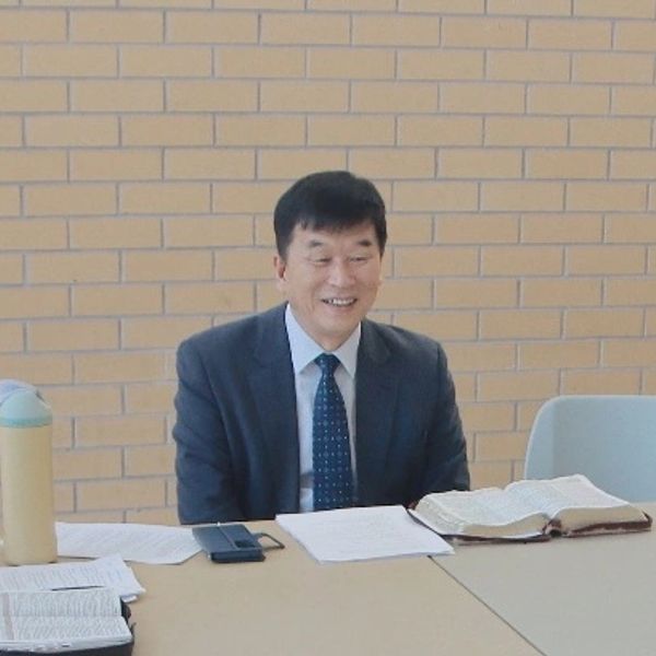 A man in a suit smiling while sitting at a table with books and papers.