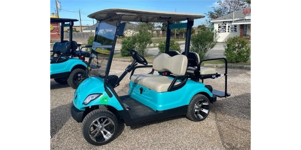 Blue golf cart with beige seats parked outdoors.