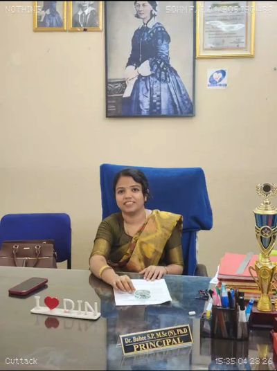 A principal seated at her desk with awards and papers.
