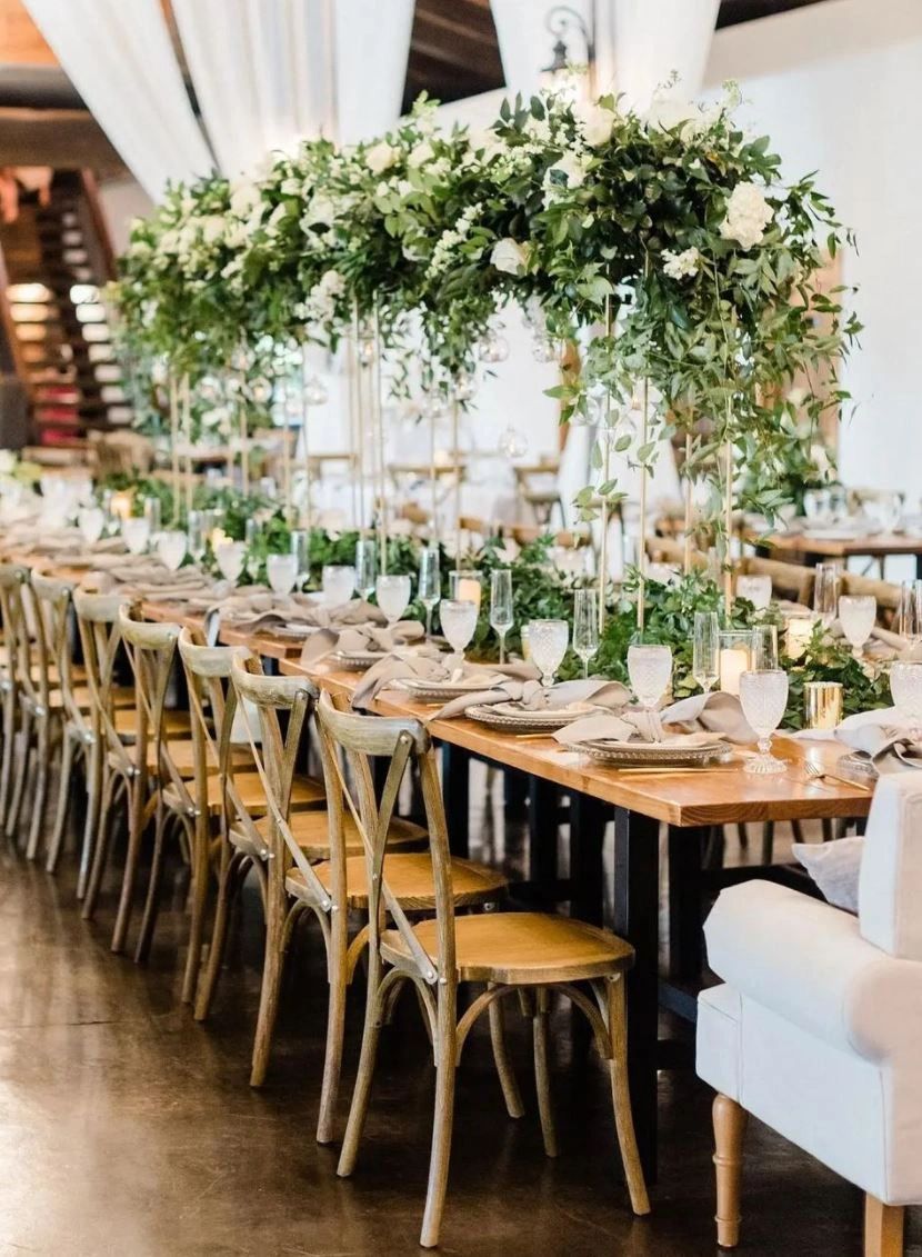 Wedding estate table setting with cross back chairs, candles and flowers and greenery. 