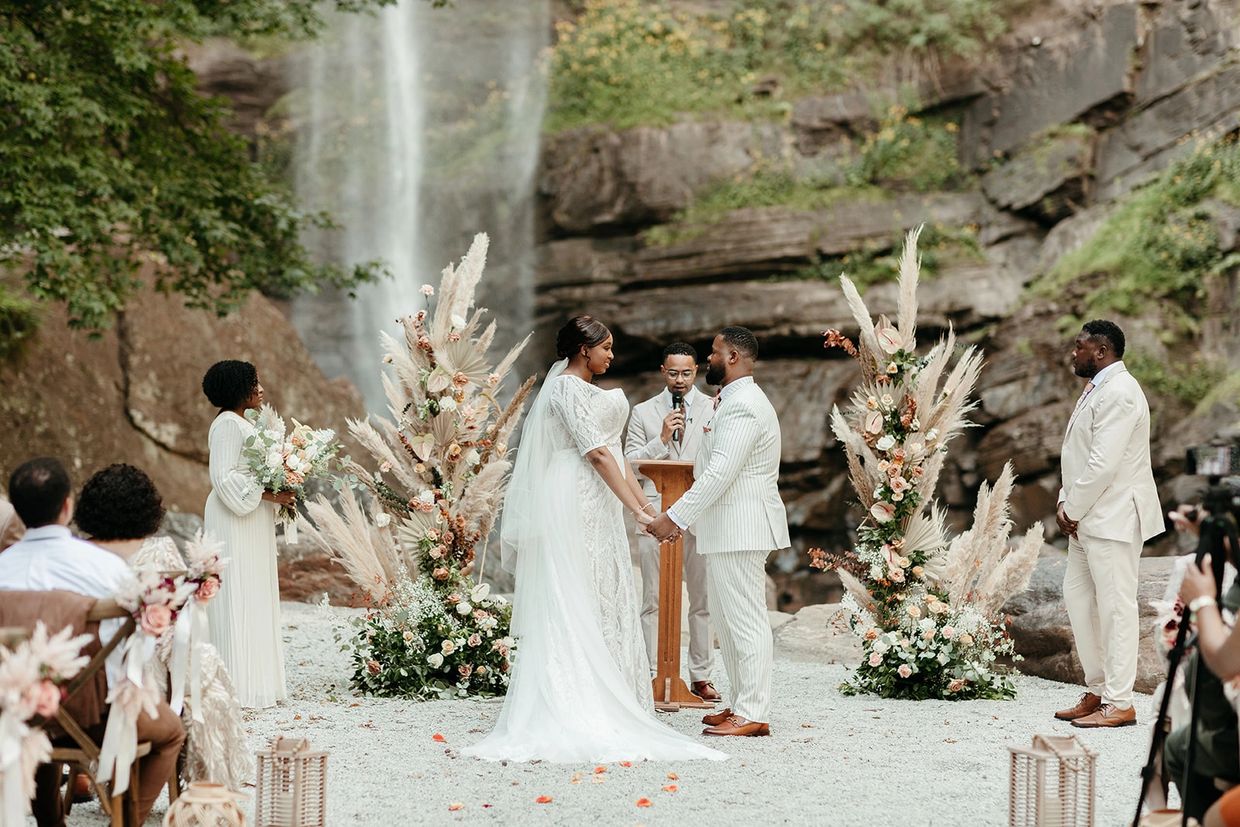 Bride & Groom wedding ceremony at Toccoa Falls with floral installation and cross-back chairs. 