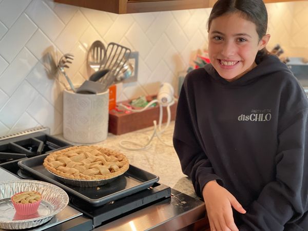 Smiling girl with homemade pies in kitchen.