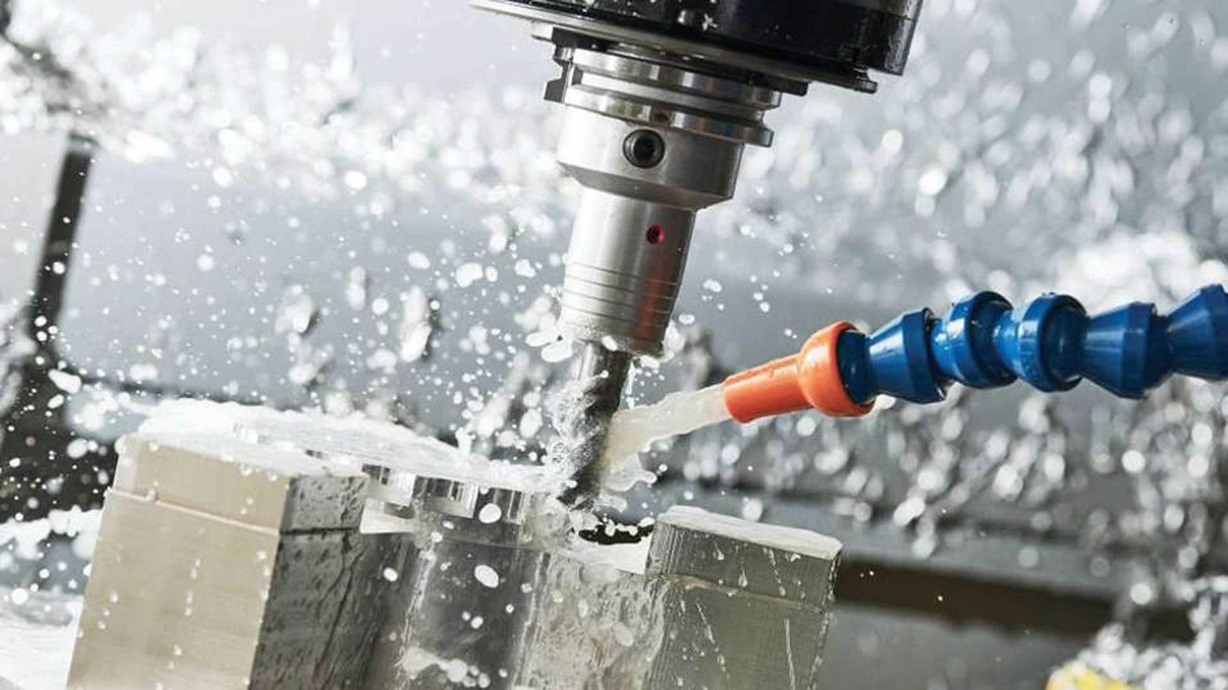 Close up of a CNC machine cutting into metal, being cooled with water