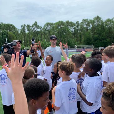 Coach engaging excited kids at a sports camp outdoors.