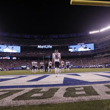 Football players stand on the field under stadium lights at MetLife.