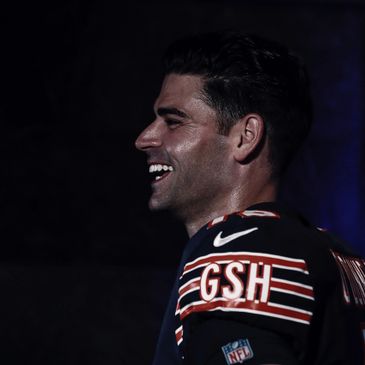 Profile of a smiling football player in a dark setting wearing a GSH jersey.