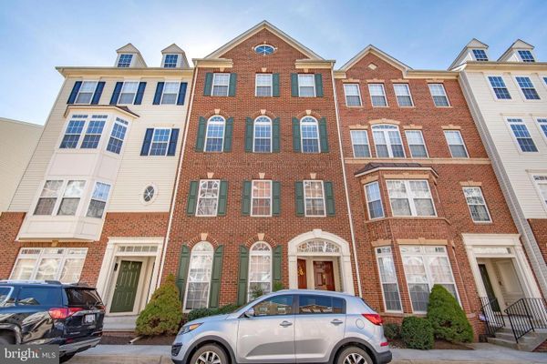 Three-story brick and siding townhouses with cars parked in front.