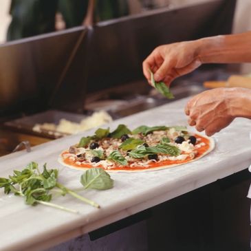 Chef preparing pizza with hand made dough and fresh ingredients