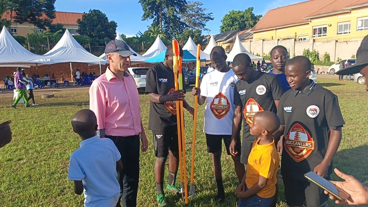 Group of people gathered outdoors, some holding sports equipment, under clear blue sky.