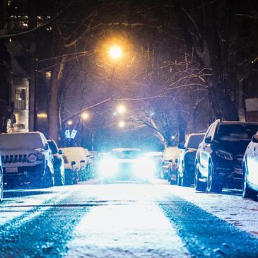 Headlights of approaching car on a dark and snowy street.