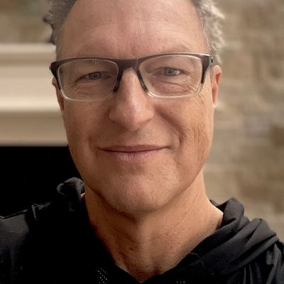 Middle-aged man smiling at the camera wearing glasses.