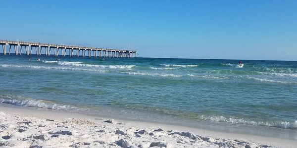 A warm sunny day at the beach looking out at the blue water watching the waves roll next to the pier