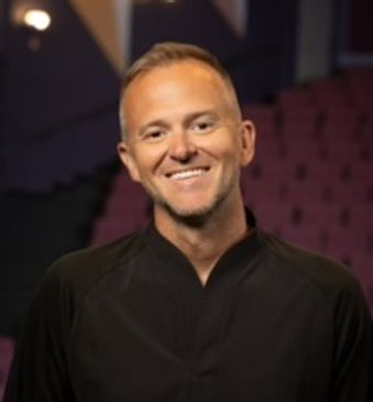 Smiling man in a black shirt.