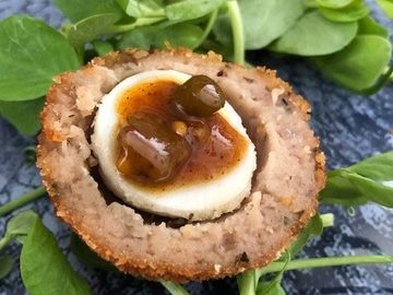 Homemade Quail's Scotch Egg Canapes with Homemade Piccalilli dressed with watercress on a blue plate