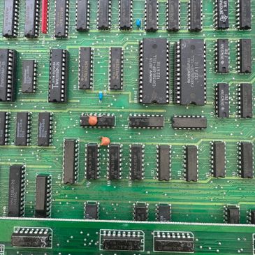 Close-up of a green circuit board with black integrated circuits and electronic components.