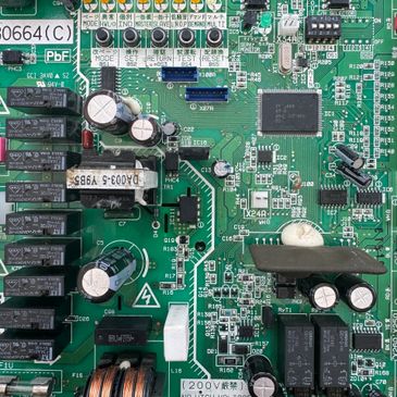 Close-up of a green electronic circuit board with capacitors and chips.