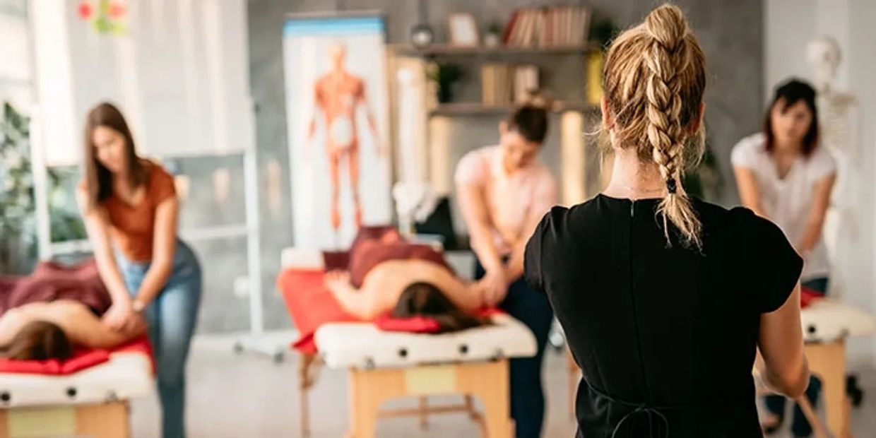A massage therapy class with students practicing on clients under instructor supervision.