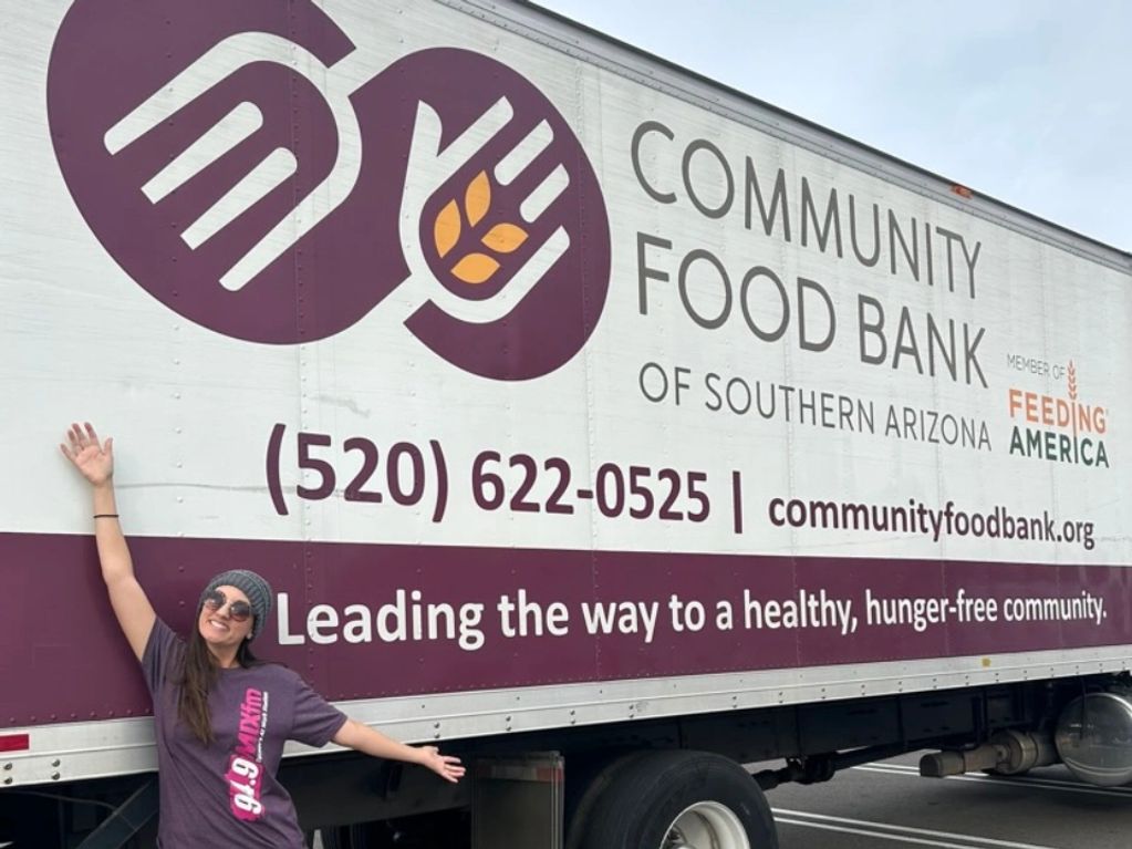 A woman poses happily in front of a Community Food Bank truck in Southern Arizona.