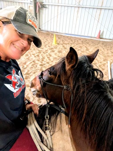 Woman taking selfie with a horse indoors.