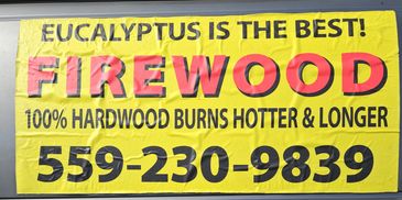 Yellow sign on a vehicle advertising eucalyptus firewood with contact number.