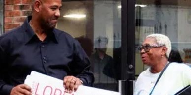 Two people smiling and interacting outside a building.