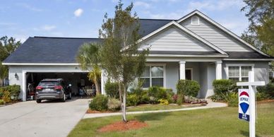 A modern single-story house with a well-kept lawn and a car parked in the driveway.