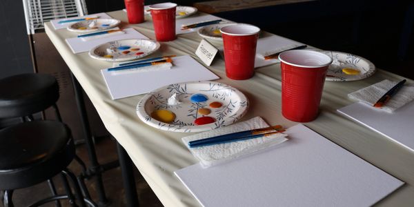 Paint supplies and canvases arranged on a table for a painting session.