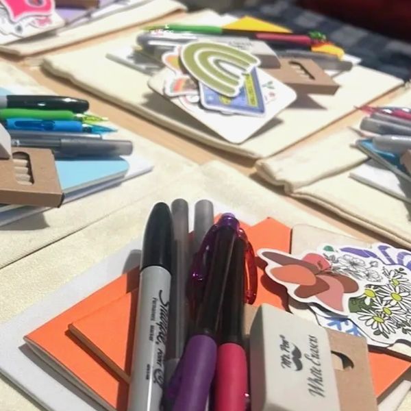 Stationery sets with pens, markers, and stickers arranged on a table.