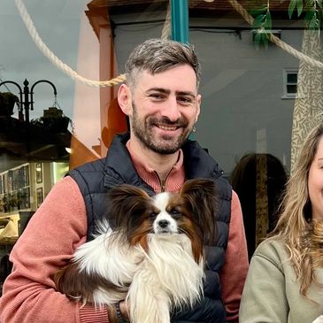 Man smiling while holding a fluffy dog outdoors.
