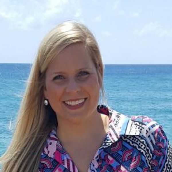 Young woman smiling at the beach with ocean background.